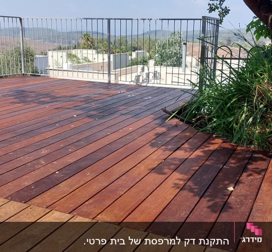 דק עץ עם קרשים מונחים ליד עץ וצמחייה